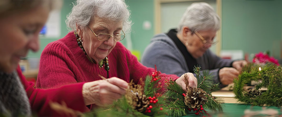 yolo-1080×450-124 Three seniors sat at a table doing holiday activities.